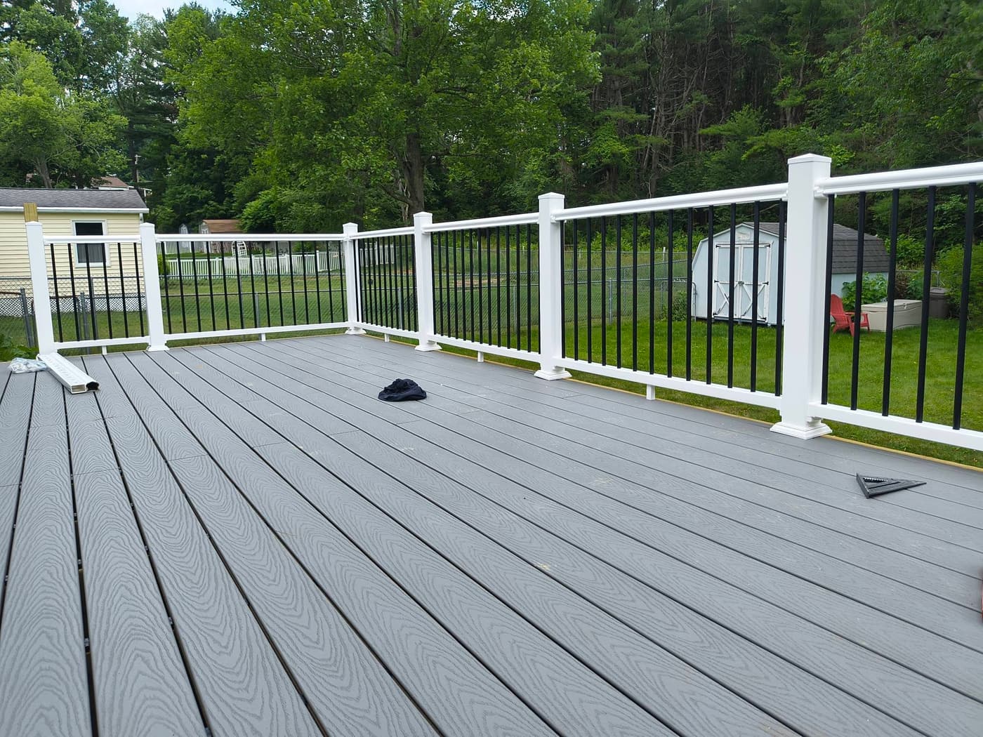 A finished composite deck with white railing, looking out over the yard, built by Dream Builders in Endicott