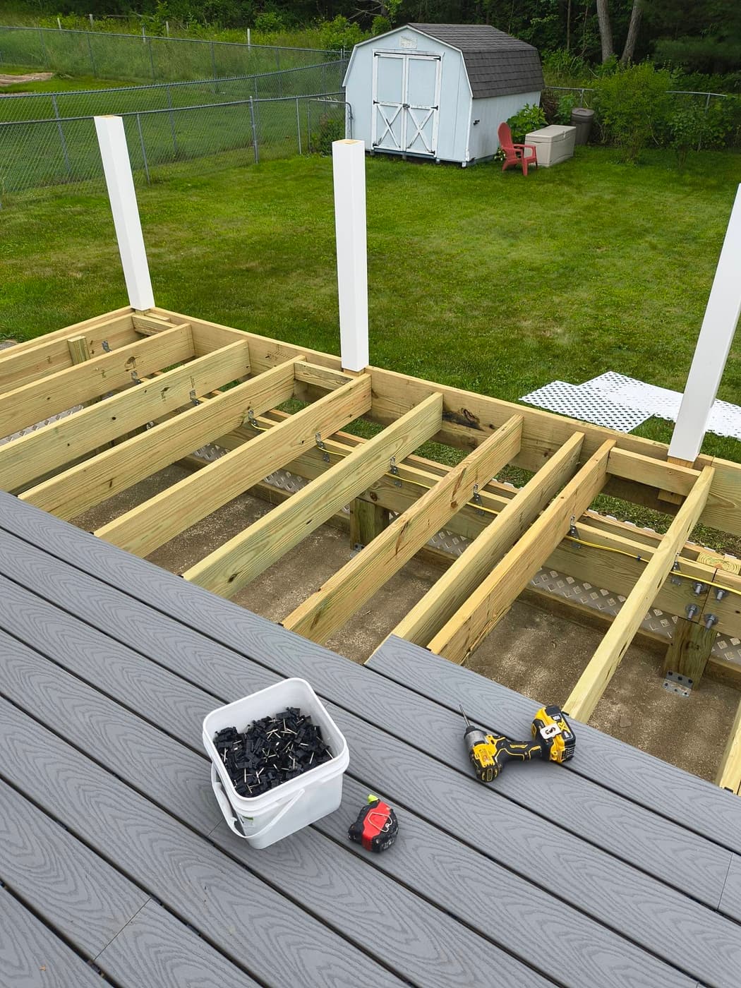 Joists and posts framed for a new deck, composite boards stacked and ready