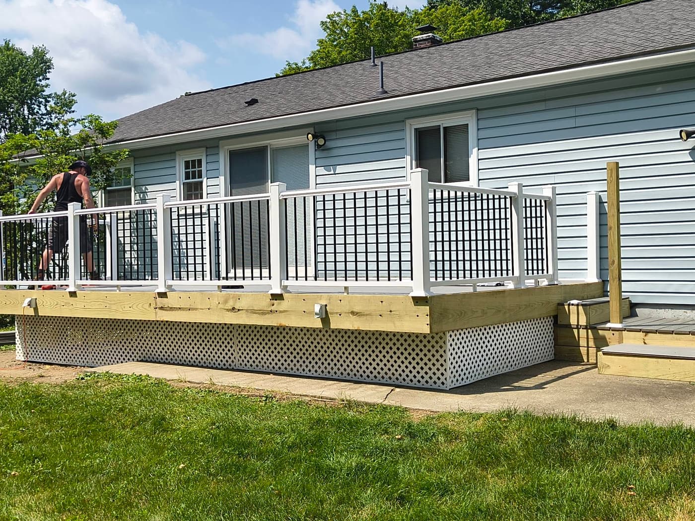 A new composite deck and white railing along the back of a light blue house